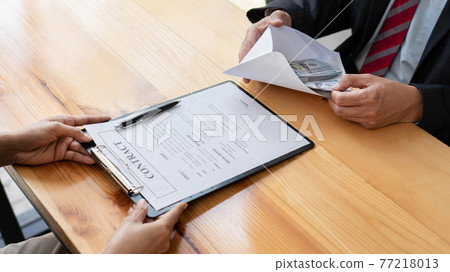 Businessman reciving money United States Dollars bills to corruption from his partner in business at working desk - bribery concept. Businessman reciving money United States Dollars bills to corruption from his partner in business at working desk - bribery concept. 77218013