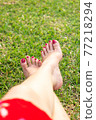 Woman foot with red nail coat on green grass. Relaxation concept. 77218294