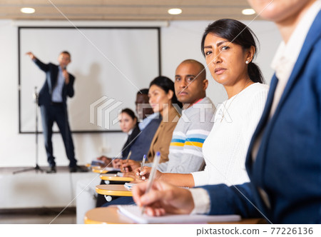 Confident woman listening to lecture at conference Confident woman listening to lecture at conference 77226136