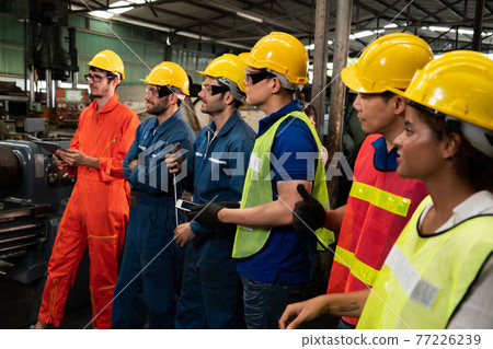 Skillful worker attending brief meeting in the factory . Skillful worker attending brief meeting in the factory . 77226239