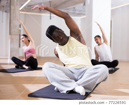 Man practicing pilates exercises at group class Man practicing pilates exercises at group class 77226591