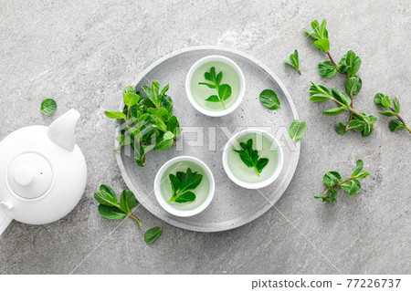 Herbal mint tea in small traditional chinese cups and fresh leaves, healthy antioxidant drink Herbal mint tea in small traditional chinese cups and fresh leaves, healthy antioxidant drink 77226737