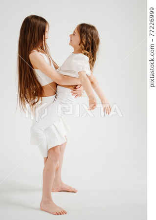 two cheerful girls with long hair in white clothes play, have fun. two cheerful girls with long hair in white clothes play, have fun. 77226999