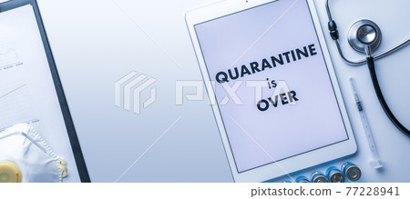 End of quarantine. Medical equipment: doctor stethoscope, hospital healthcare charts, syringe with needle and white tablet with text on screen. Quarantine is over concept. End of quarantine. Medical equipment: doctor stethoscope, hospital healthcare charts, syringe with needle and white tablet with text on screen. Quarantine is over concept. 77228941