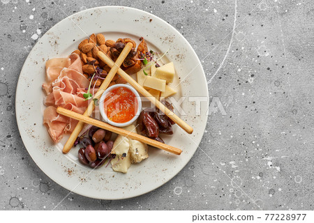 Set of snacks for wine. Prosciutto, parmesan, gorgonzola, almonds, olives, bread chips, mostard fruit confiture on gray marble background 77228977