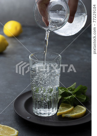 Sparkling water in glass, pouring water in glass. 77229184