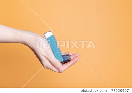 Hand holds inhaler to treat asthma. World Asthma Day. Concept of allergy care. Copy space Hand holds inhaler to treat asthma. World Asthma Day. Concept of allergy care. Copy space 77230497