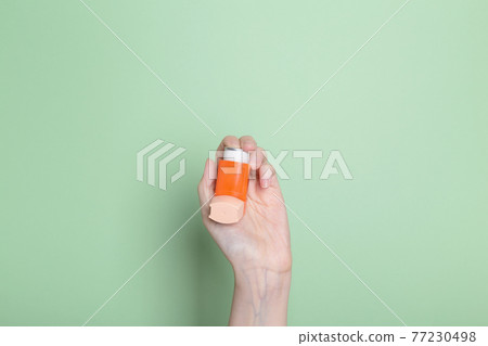 Hand holds inhaler to treat asthma. World Asthma Day. Concept of allergy care Hand holds inhaler to treat asthma. World Asthma Day. Concept of allergy care 77230498