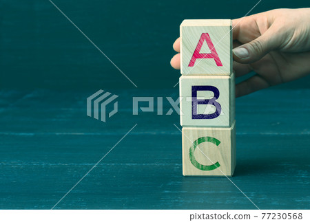 hand holds wooden cubes with letters A, B, C. Concept of preschool education. Simple truths and a list of achievements and goals hand holds wooden cubes with letters A, B, C. Concept of preschool education. Simple truths and a list of achievements and goals 77230568