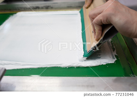 Serigraphy silk screen print process at clothes factory. Frame, squeegee and plastisol color paints Serigraphy silk screen print process at clothes factory. Frame, squeegee and plastisol color paints 77231046