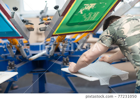 Serigraphy silk screen print process at clothes factory. Frame, squeegee and carousel Serigraphy silk screen print process at clothes factory. Frame, squeegee and carousel 77231050