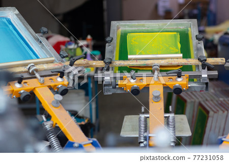 Carousel Frame, squeegee and plastisol color paint Serigraphy silk screen print process at clothes factory. Carousel Frame, squeegee and plastisol color paint Serigraphy silk screen print process at clothes factory. 77231058