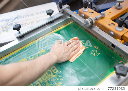 Serigraphy silk screen print process at clothes factory. Cleansing Frame, squeegee and plastisol color paints Serigraphy silk screen print process at clothes factory. Cleansing Frame, squeegee and plastisol color paints 77231083