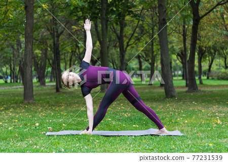 pretty blond young woman practice yoga asana in summer park 77231539