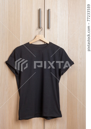 Black shortsleeve cotton tshirt hanging on a wardrobe door handle Black shortsleeve cotton tshirt hanging on a wardrobe door handle 77233589