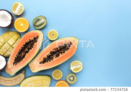 Different fresh tropical cut fruits on a blue background Different fresh tropical cut fruits on a blue background 77234726