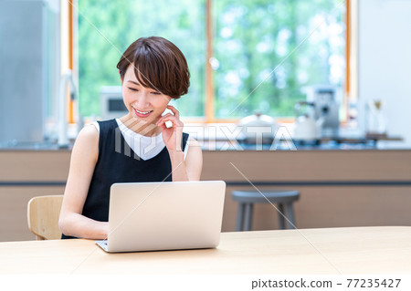 A middle-aged woman who uses a laptop in the living room. A middle-aged woman who uses a laptop in the living room. 77235427