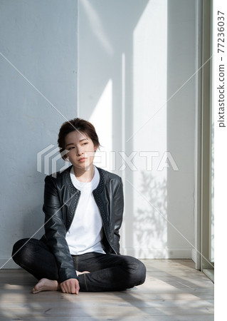 Genderless LGBT boy-like girl wearing a leather jacket and sitting on the floor Genderless LGBT boy-like girl wearing a leather jacket and sitting on the floor 77236037