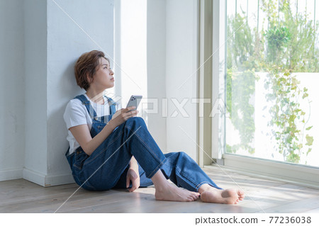 Genderless LGBT girl like a boy A woman sitting on the floor and looking out with her smartphone in her hand 77236038