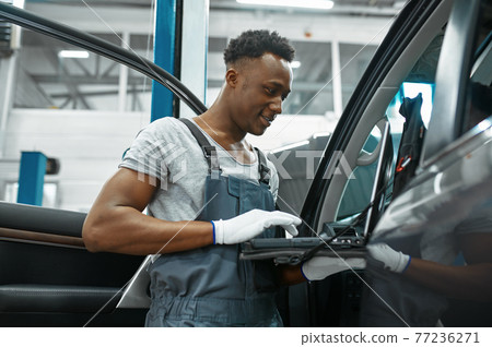 Male mechanic using laptop, car service 77236271