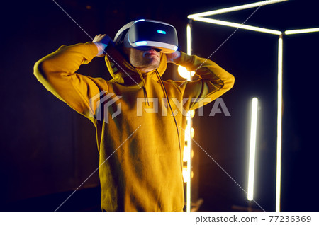 Gamer plays the game using virtual reality helmet Gamer plays the game using virtual reality helmet 77236369