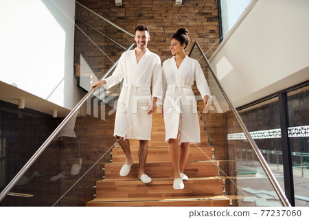 Portrait of young couple in spa resort, walking down the stairs. Portrait of young couple in spa resort, walking down the stairs. 77237060