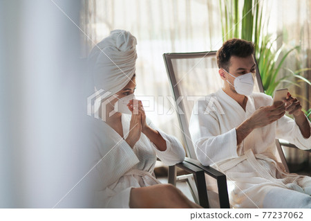 Young couple sitting and relaxing in spa resort, coronavirus concept. Young couple sitting and relaxing in spa resort, coronavirus concept. 77237062