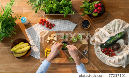 Top view of unrecognizable woman preparing fruit smoothie, sustainable lifestyle. 77237101