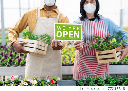 Obscured people working in greenhouse in garden center, store open after coronavirus lockdown. 77237848