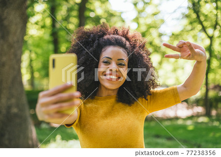 Pretty afro girl taking a selfie laughing. Pretty afro girl taking a selfie laughing. 77238356