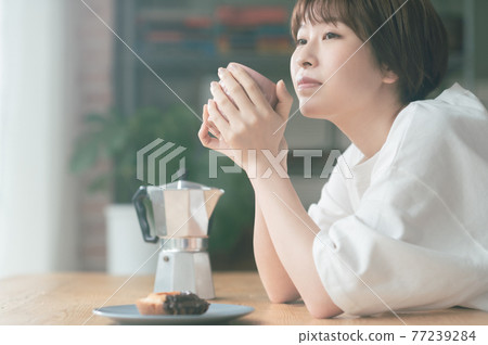 Young woman drinking coffee in the living room 77239284