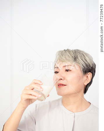Portrait of a senior asian woman with a glass of milk. 77239476