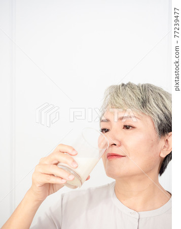 Portrait of a senior asian woman with a glass of milk. 77239477