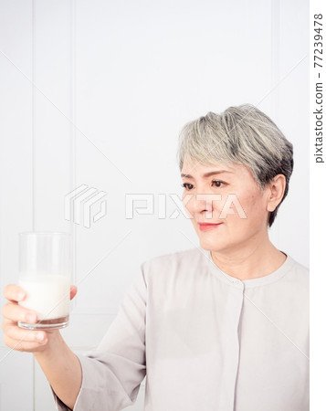Portrait of a senior asian woman with a glass of milk. 77239478
