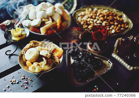Eastern sweets. Dried fruits. Nuts. Haze from an extinguished candle. 77240366