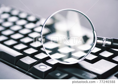 Magnifying glass on the keys of a black computer keyboard Magnifying glass on the keys of a black computer keyboard 77240388