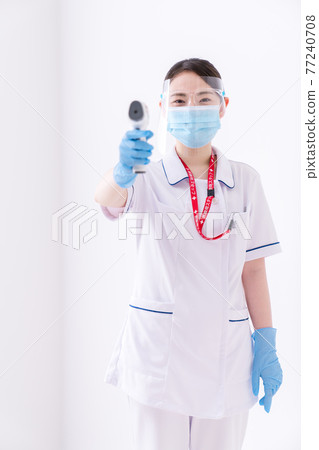 A nurse measuring body temperature with a non-contact thermometer 77240708