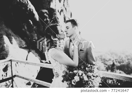 Happy beautiful wedding couple bride and groom at wedding day outdoors on the mountains rock. Happy marriage couple outdoors on nature, soft sunny lights Happy beautiful wedding couple bride and groom at wedding day outdoors on the mountains rock. Happy marriage couple outdoors on nature, soft sunny lights 77241647