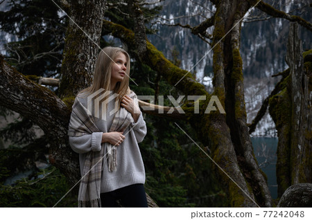 Girl sits on a tree and meditates near lake Ritsa in Abkhazia 77242048