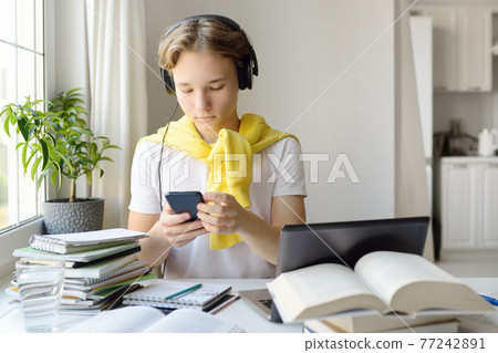 Tennager boy study at home. Online education and distance learning for children. School boy doing his homework using gadgets. Lectures and lessons on the internet for high school students Tennager boy study at home. Online education and distance learning for children. School boy doing his homework using gadgets. Lectures and lessons on the internet for high school students 77242891