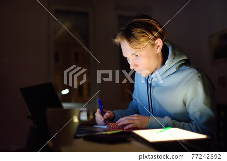 Shocked teenger studying night at home with laptop and tablet pc. Online learning, distance lessons, freelance - modern lifestyle Shocked teenger studying night at home with laptop and tablet pc. Online learning, distance lessons, freelance - modern lifestyle 77242892