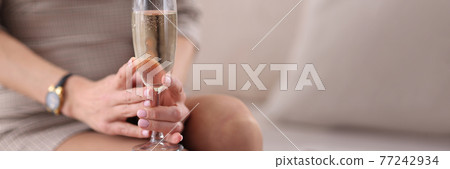 Woman holds glass of champagne in her hands Woman holds glass of champagne in her hands 77242934