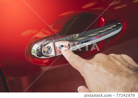 Human hand was pressing to keyless entry button on the car door handle of the red car 77242979