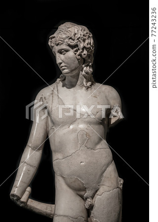 Ancient almost destroyed marble statue of a young naked Roman Noble man isolated at black background, Rome, Italy, details, closeup Ancient almost destroyed marble statue of a young naked Roman Noble man isolated at black background, Rome, Italy, details, closeup 77243236