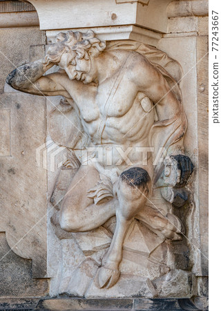 Ancient sculpture of funny, tricky and joyful dickens in historical downtown of Dresden, Germany, details, closeup. Concept of art and historical heritage. 77243667