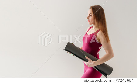 Beautifull young blond sportswoman holding yoga or fitness mat isolated over grey background. Healthy life, keep fit concepts. Web banner Beautifull young blond sportswoman holding yoga or fitness mat isolated over grey background. Healthy life, keep fit concepts. Web banner 77243694
