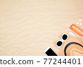 top view travel beach background concept with sunglasses ,smart phone , sunscreen and beach hat on sand. 77244401