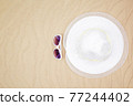 top view travel beach background concept with sunglasses and beach hat on sand. 77244402