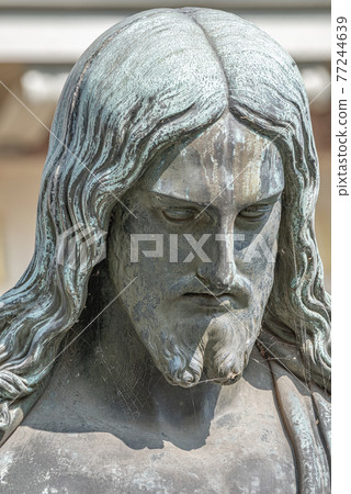 Old statue of Jesus Christ with open arms at the ancient church called in German Friedenskirche, located at Sanssouci City Park entrance in Potsdam, Germany. 77244639