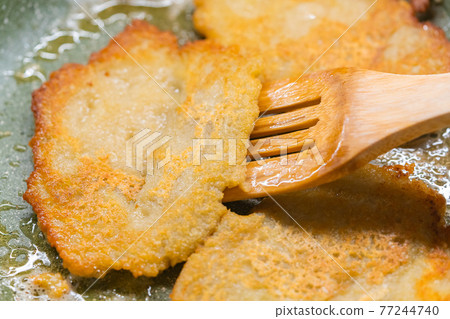 Potato pancakes on green frying pan 77244740
